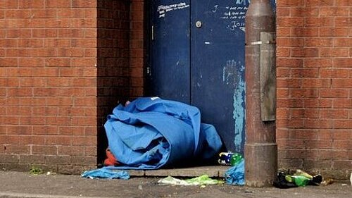 Abandoned sleeping bag rolled up by a doorway