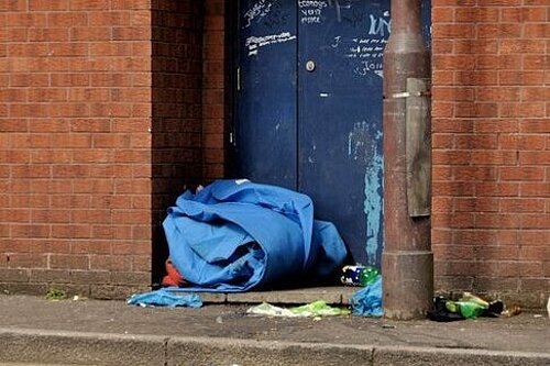 Abandoned sleeping bag rolled up by a doorway